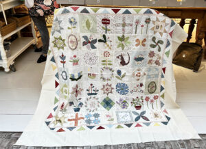 Bij Quilt Studio het Gooi komen vaak quiltvriendinnen winkelen. Gezellige een dagje uit en aansluitend een lunch in onze dorpsherberg. Dineke kwam met haar quiltclubje shoppen en een achterkant uitzoeken bij deze prachtige miniversie van de Stonefields quilt. Kijk eens hoe leuk deze rand is! Ze heeft de Flying Geese van het oorspronkelijke ontwerp gekanteld. Wat een idee..... Alle aanwezige klanten in de winkel hebben even meegenoten van deze vrolijke quilt. Dank je wel dat hij op de foto mocht Dineke!