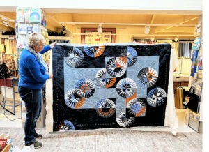 Deze prachtige quilt is door Janny zelf ontworpen! Haar man heeft geholpen bij het tekenen van de cirkels. Gezamenlijk besloten we het roestbruin/oranje aan al het blauw toe te voegen. Wat een spannende quilt is het geworden Janny!