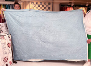 Judith had haar prachtige Whole Cloth Quilt mee. Ze maakte hem van onze Linen Texture Duck Egg stof. Dit soort patronen quilt superfijn omdat er geen naadjes in zitten. De quilt heeft aan beide kanten dezelfde stof. Zo kun je het mooie quiltwerk aan beide kanten goed zien. Opmerking van Judith: naarmate je langer quilt worden de steekjes kleiner. Je krijgt dan de slag goed te pakken. Judith gebruikte er een Aunt Becky bij (klik). Volgens haar was het zonder dit handige hulpstukje niet zo makkelijk gegaan. Top dat hij op de foto mocht Judith!